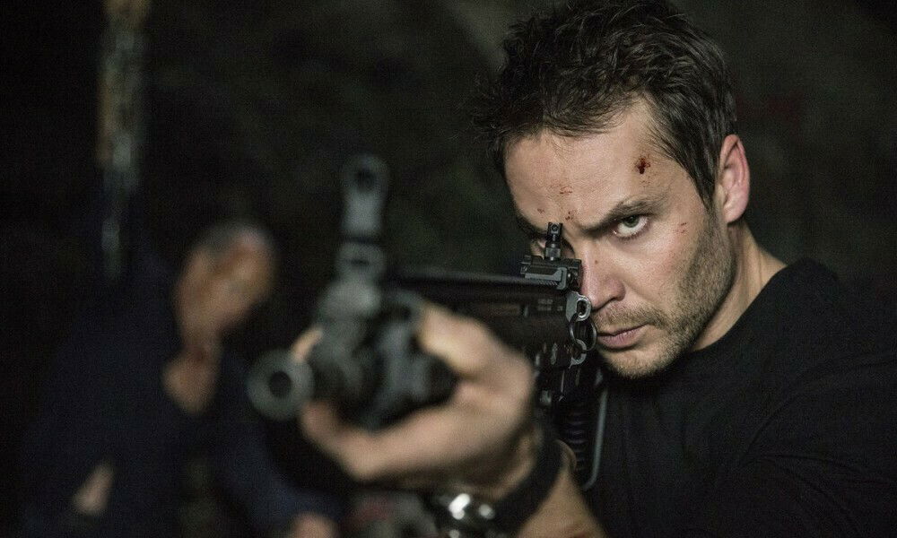 Clicca per vedere l'immagine originale Taylor Kitsch imbraccia un mitra nel ruolo di Ghost, il terrorista di American Assassin