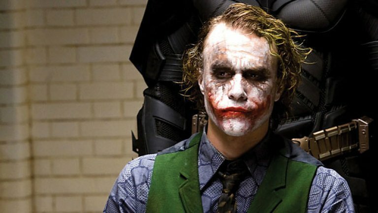 Joker (Heath Ledger) seduto ed alle sue spalle l'ombra di Batman (Christian Bale)