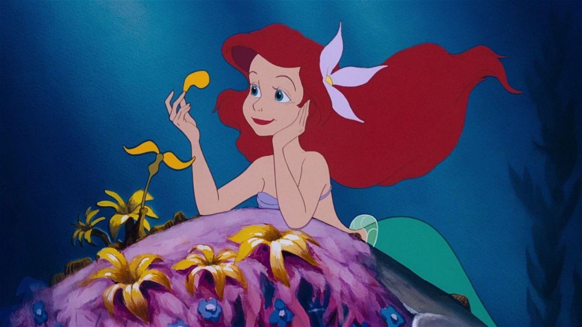 La sirenetta Ariel che contempla i petali di un fiore