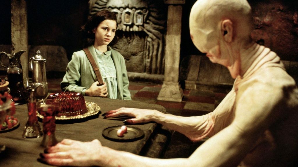 Clicca per vedere l'immagine originale L'Uomo Pallido siede alla tavola, con i propri occhi sopra un piattino, mentre Ofelia lo guarda allibita