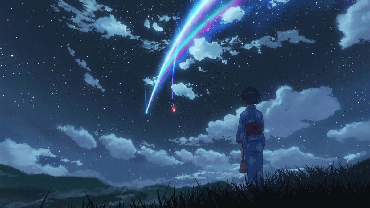 Una cometa illumina un cielo pieno di stelle, mentre una ragazza guarda la scena
