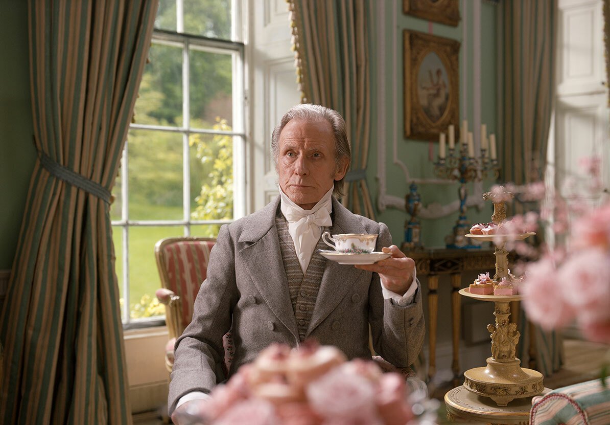 Il padre di Emma regge una tazza e piattino da tè con espressione sconcertata