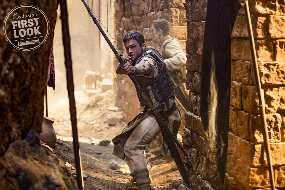 Taron Egerton armato di arco in una scena del film