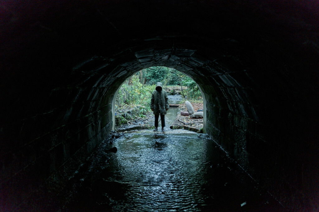 Clicca per vedere l'immagine originale Un misterioso personaggio in fondo a un tunnel osserva lo spettatore