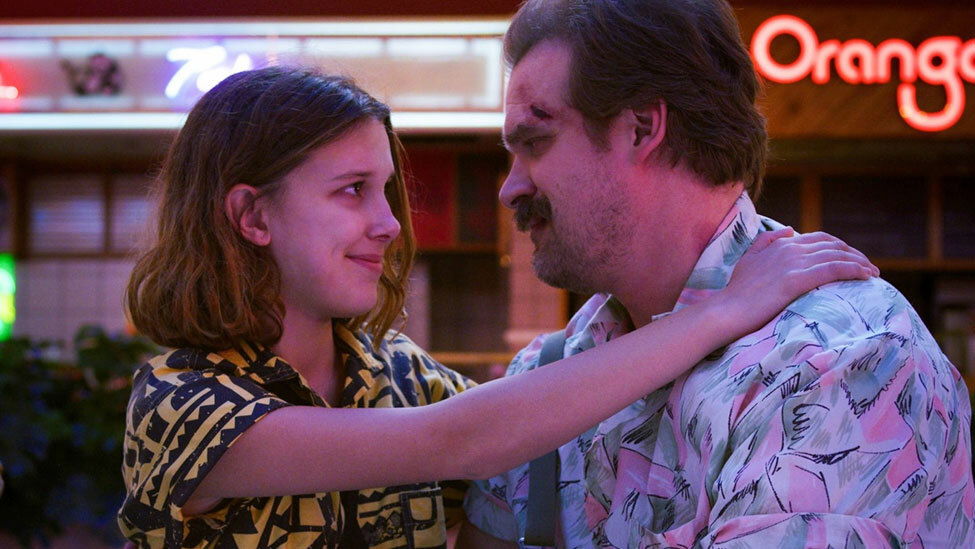 Hopper e Undici insieme in una scena di Stranger Things David Harbour e Millie Bobby Brown si sorridono