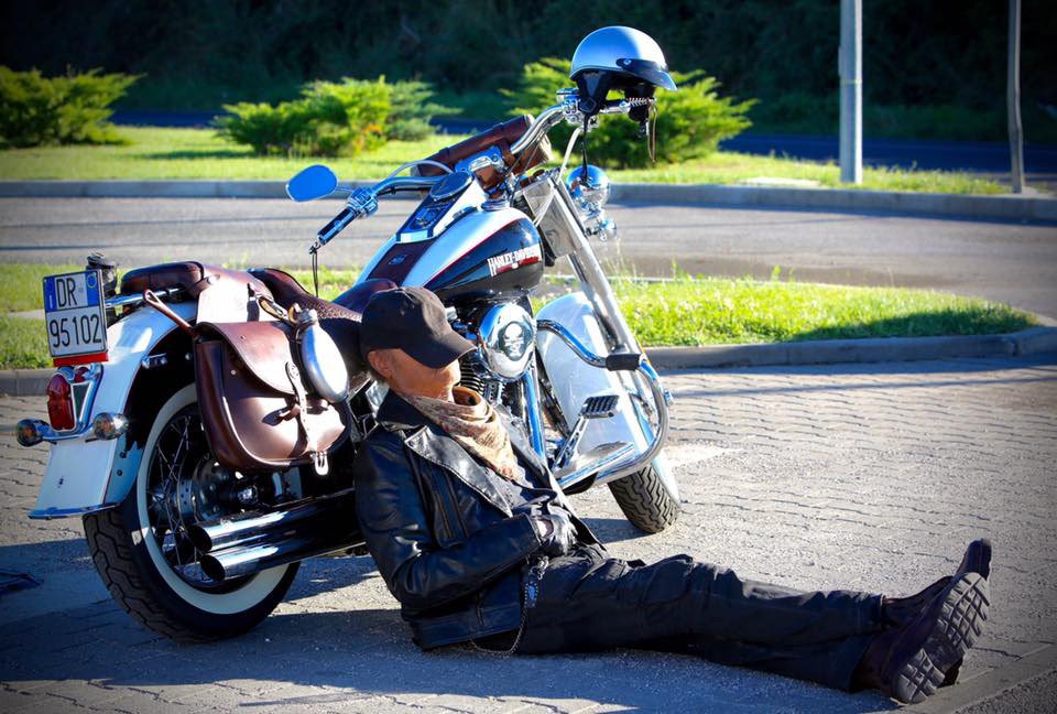 Terence Hill appoggiato a un motocicletta durante un pisolino