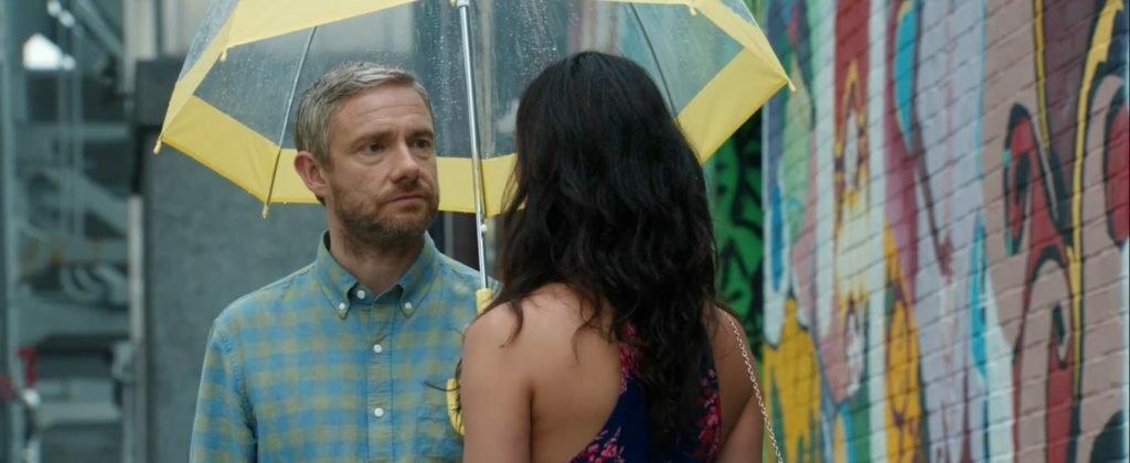 Martin Freeman riparato sotto l'ombrello con Morena Baccarin in una scena del film