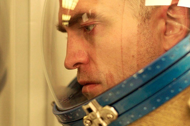 Primo piano di Robert Pattinson col casco d'astronauta in una scena del film