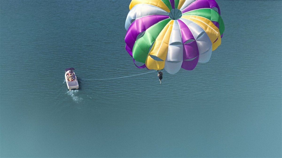 Una scena di parasailing inquadrata dall'alto, su un mare limpido.