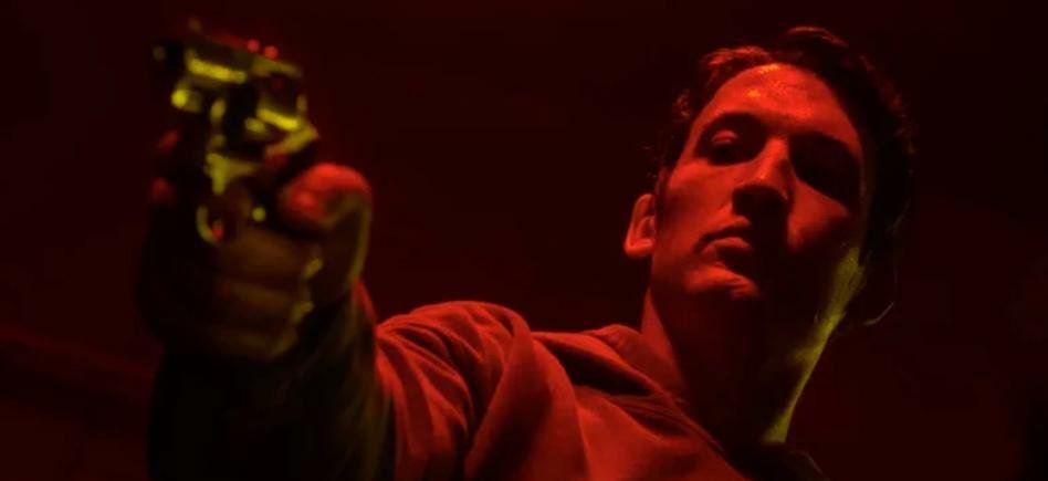 Miles Teller punta la pistola in un frame d Too Old To Die Young