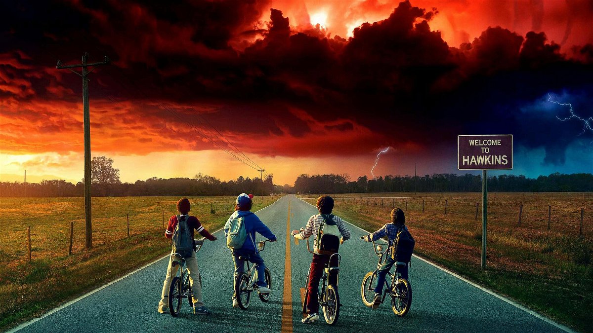 Lucas, Dustin, Mike e Will, tutti in bici di fronte a un cielo rosso in un'immagine promozionale di Stranfe