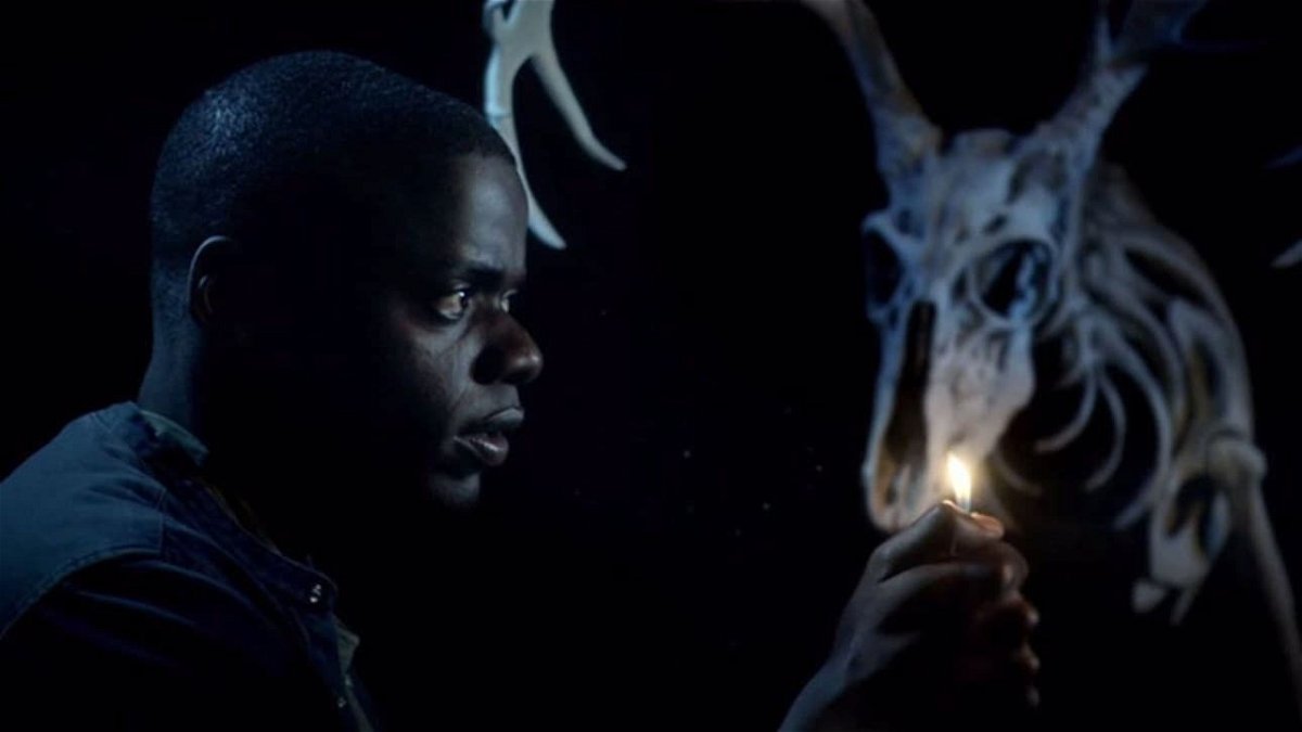 Daniel Kaluuya cammina in un ambente buio con la luce di un accendino