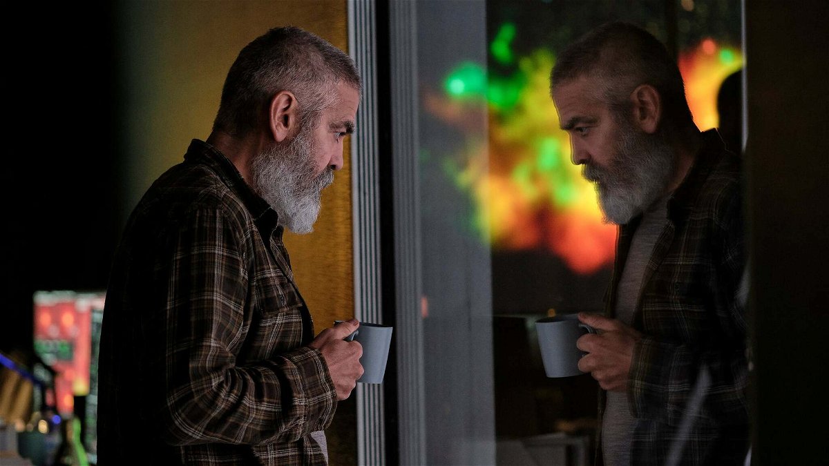 Mezza figura di George Clooney allo specchio con tazza in mano in una scena di The Midnight Sky