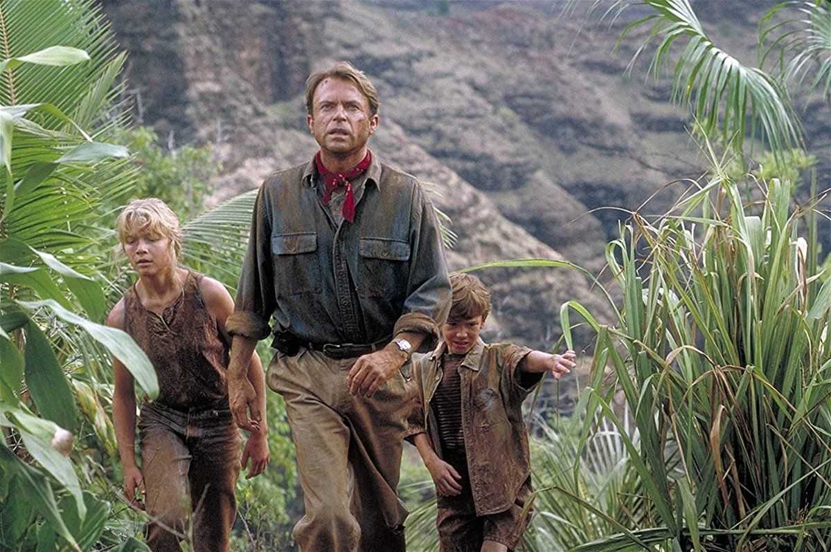 Jurassic Park - Un uomo e due bambini avanzano nella vegetazione